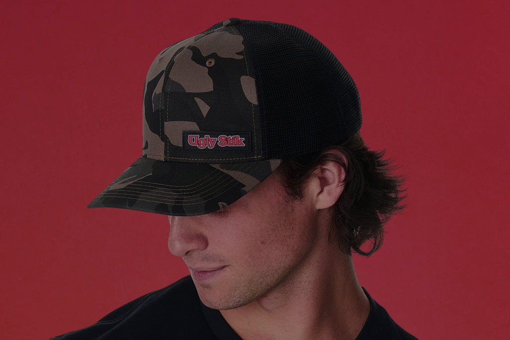 Person wearing a camouflage baseball cap with a logo on a red background