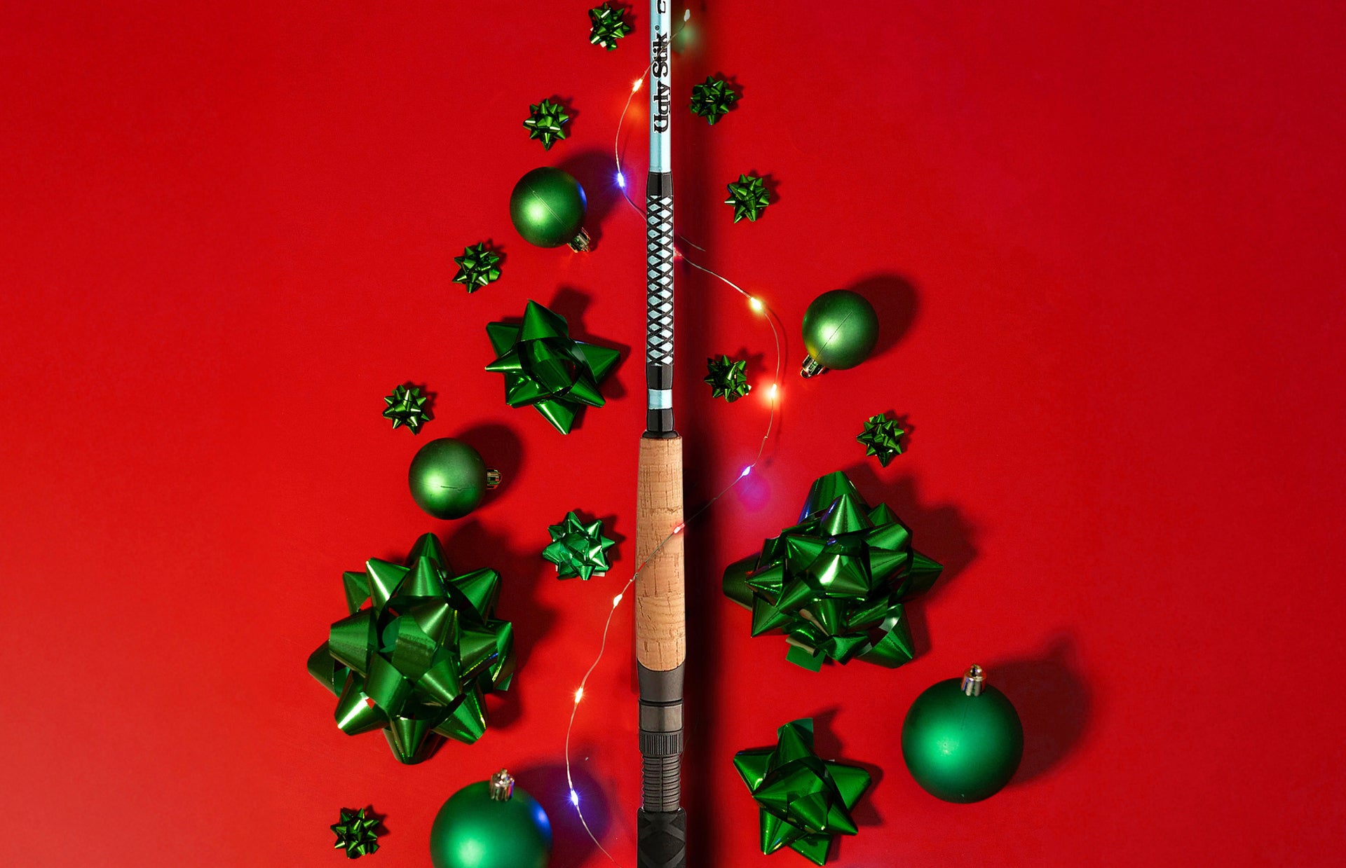 Fishing rod with green Christmas ornaments on a red background