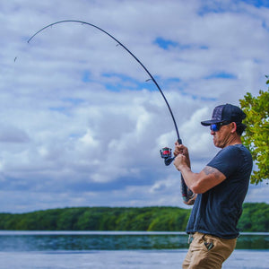 Angler fighting a fish with a heavily bent Ugly Stik spinning rod on open water.