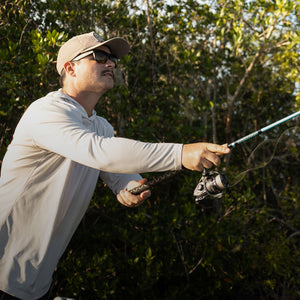 Angler casting an Ugly Stik spinning rod along a mangrove shoreline.