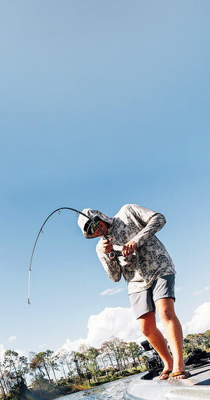 Bass angler fighting a fish from a boat with an Ugly Stik rod fully loaded.