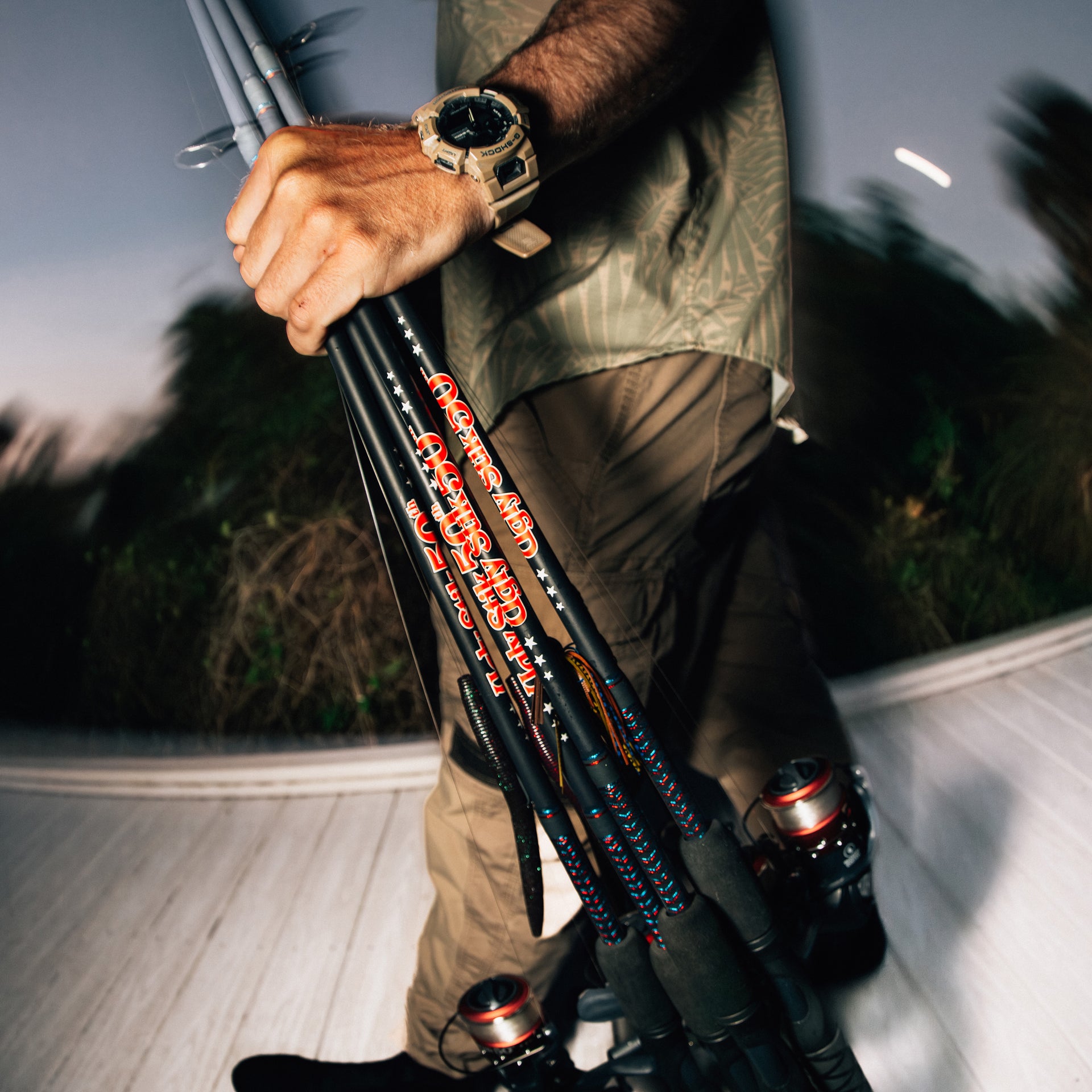 Man holding a few Ugly Stik 50th Anniversary Spinning Combos with a blurred background. 