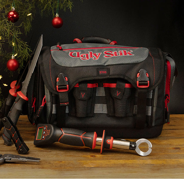 Ugly Stik branded tackle bag with tools on a wooden surface, Christmas decorations in the background