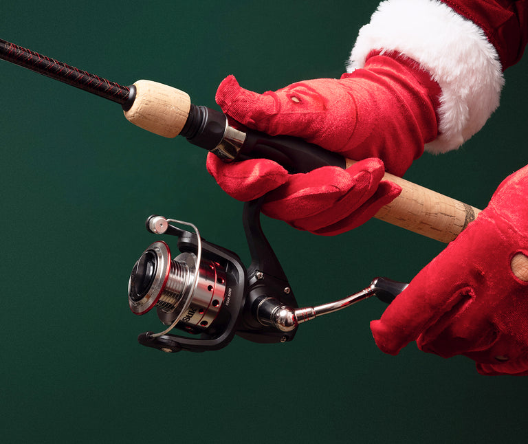 Ugly Stik fishing rod held by a hand wearing red gloves against a green background