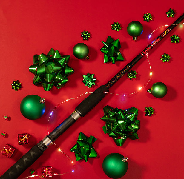 Ugly Stik GX2 fishing rod with green Christmas ornaments on a red background
